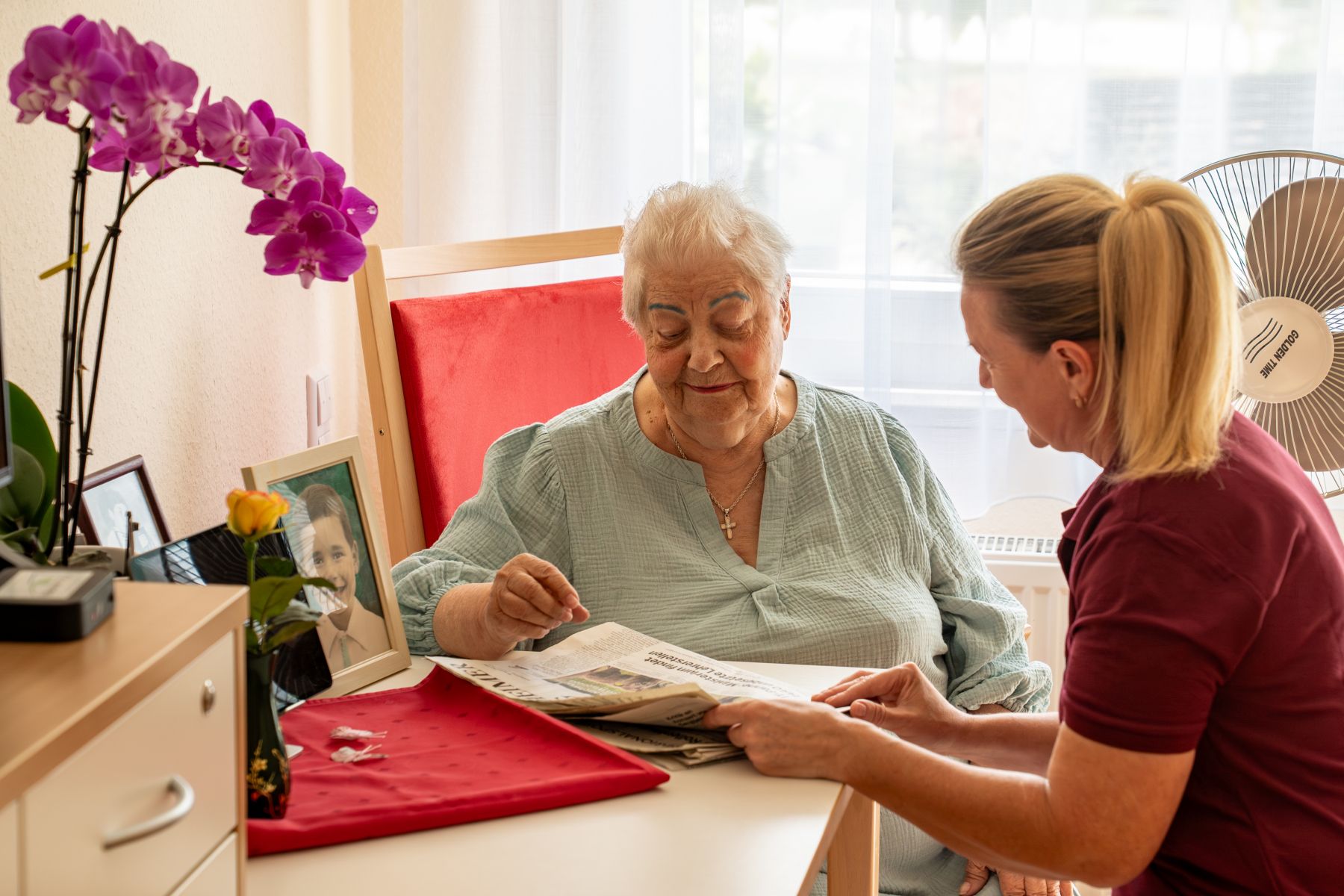 Seniorin liest gemeinsam mit Pfleger Zeitung