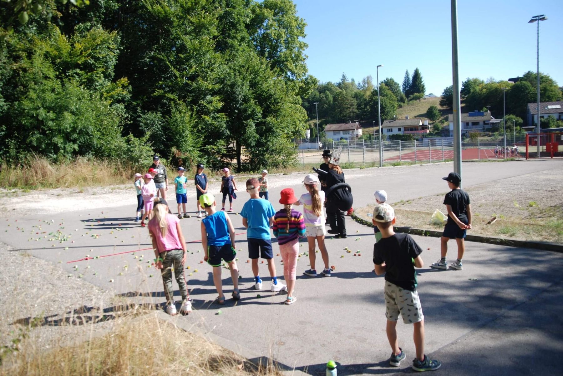 Kinder spielen ein Gruppenspiel im Freien, angeleitet von zwei verkleideten Personen.