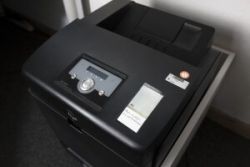 Das Bild zeigt einen Aktenvernichter mit Bedienfeld, Etikett und Prüfplakette, aufgestellt in einem Büro.