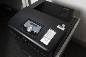 Das Bild zeigt einen Aktenvernichter mit Bedienfeld, Etikett und Prüfplakette, aufgestellt in einem Büro.